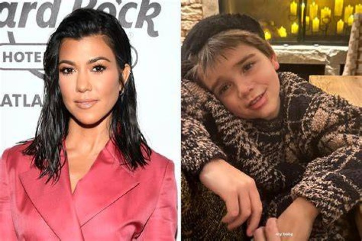 Kourtney Kardashian holds hands with Travis Barker while wearing a yellow sweatshirt.